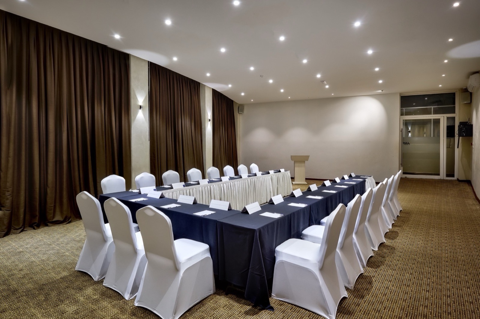 A Skyz Hotel Kampala conference hall set up in U-shape banquet style with navy tablecloths and a lectern