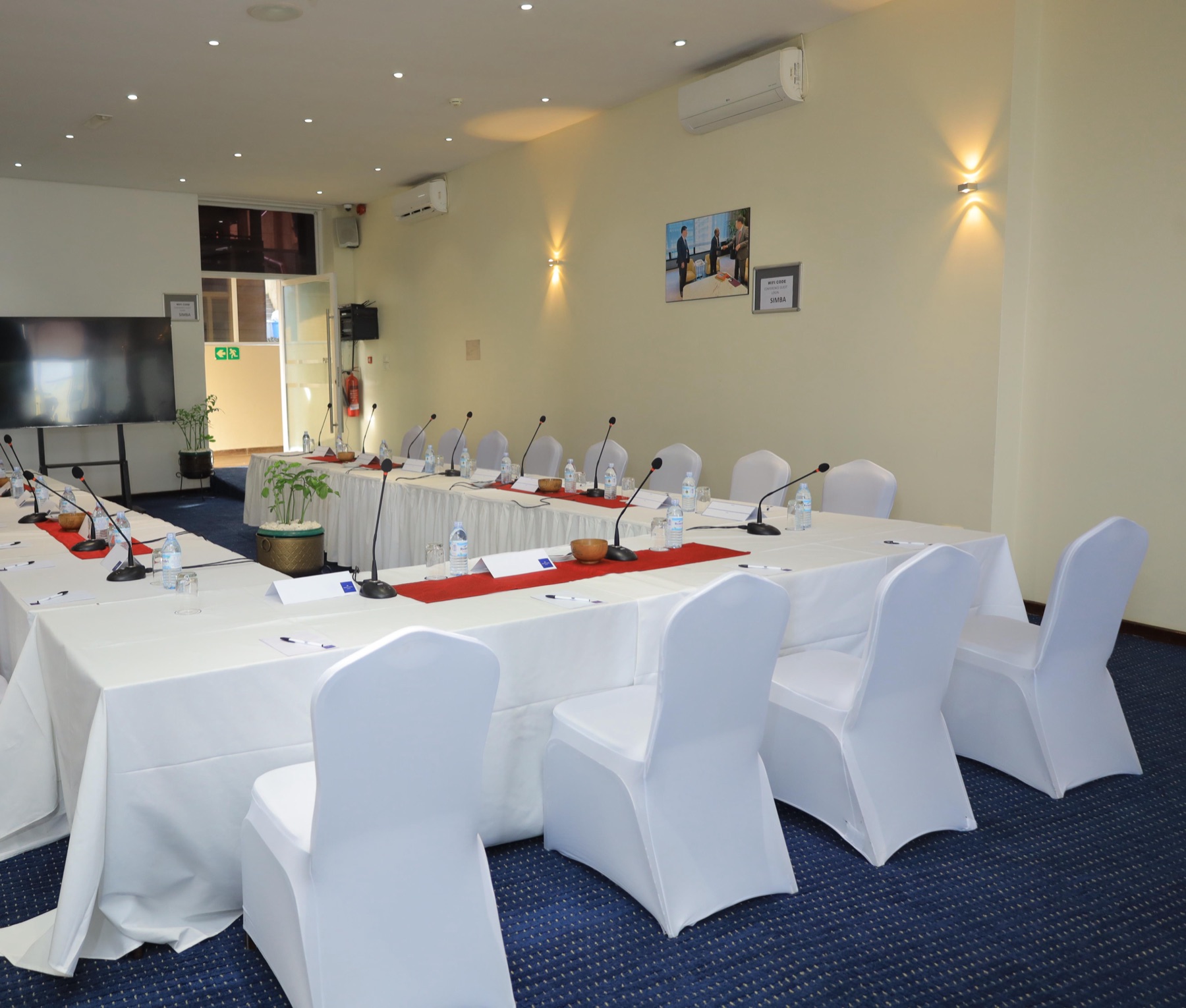 A Skyz Hotel Kampala meeting room set up in U-shape style with round-back chairs and red table runners