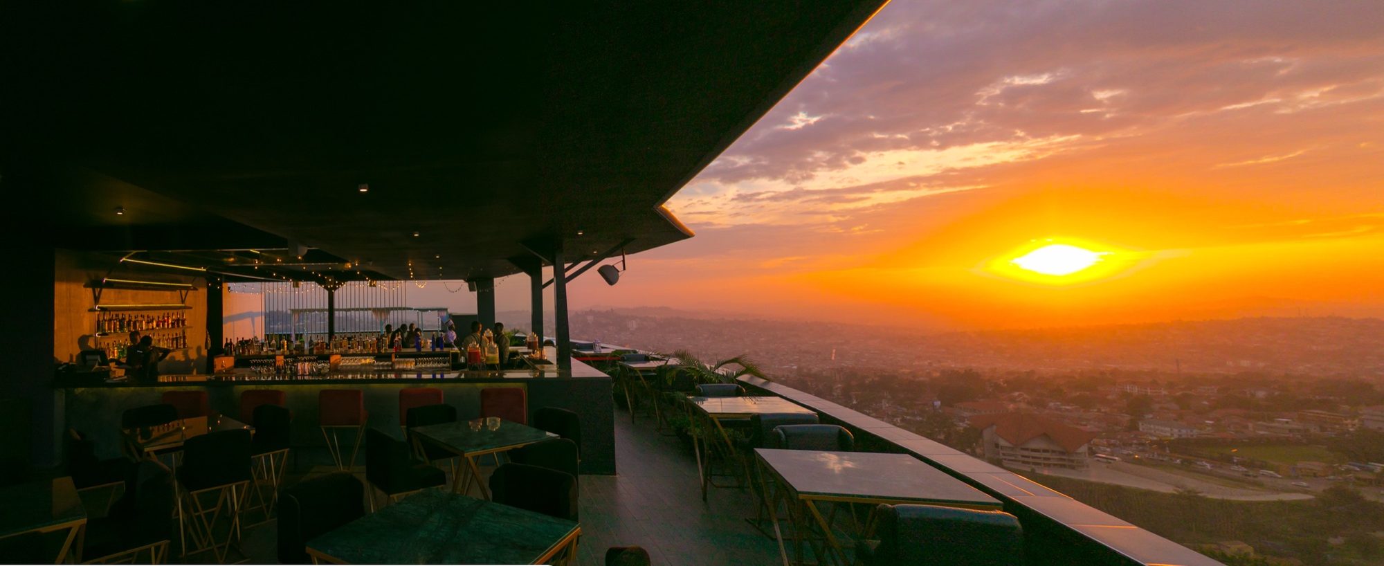 Ninety9 Rooftop lounge with a pergola at dusk overlooking Kampala