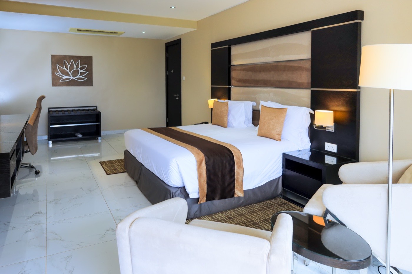 Guest room bed with padded headboard and bedside lighting at Skyz Hotel Kampala